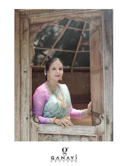 A beautifully framed shot of Lavanya, looking out from a rustic wooden window. Her traditional attire creates a timeless and poetic image.