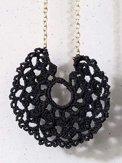 The black crochet lace pendant is a versatile piece that adds a touch of bohemian elegance to any outfit. It's a perfect example of our detailed thread jewellery.
