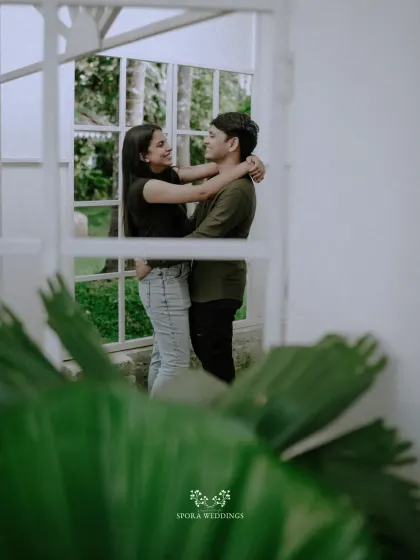 A romantic embrace framed by a window, creating a sense of intimacy and a beautiful, layered composition.