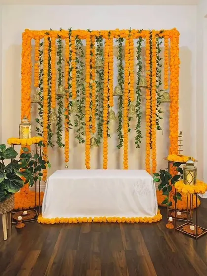 A traditional backdrop of marigold garlands and temple bells. This versatile setup is perfect for Ganesh Chaturthi, a baby shower, or any festive pooja at home.