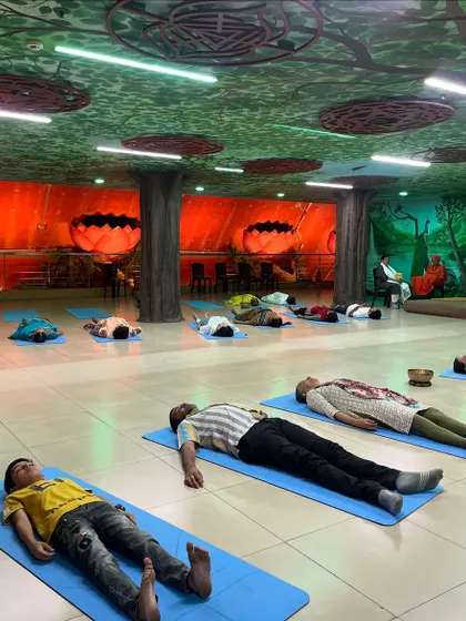 Participants in a sound healing session in Bangalore, resting in Savasana. The unique, forest-themed room adds to the tranquil atmosphere, helping them connect with nature and their inner selves.