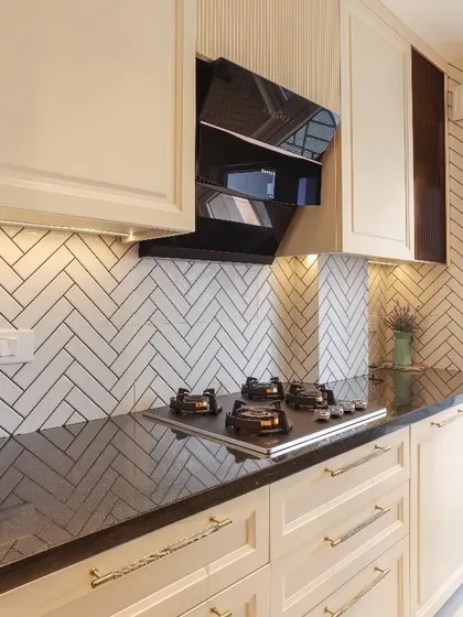Another angle of the classic kitchen, showcasing the under-cabinet lighting that illuminates the black granite countertop and the elegant, fluted panel detail next to the chimney.