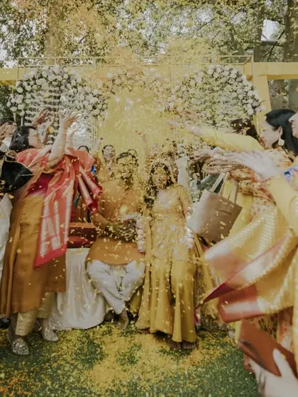 An explosion of yellow as friends and family shower the couple with marigold petals. This action shot perfectly encapsulates the vibrant energy of a Haldi celebration.