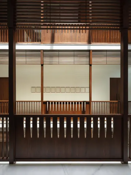 A view across the central atrium, showing the intricate layers of timber screens and railings that define the corridors. This design, inspired by 'wada' architecture, promotes visual connection between floors.