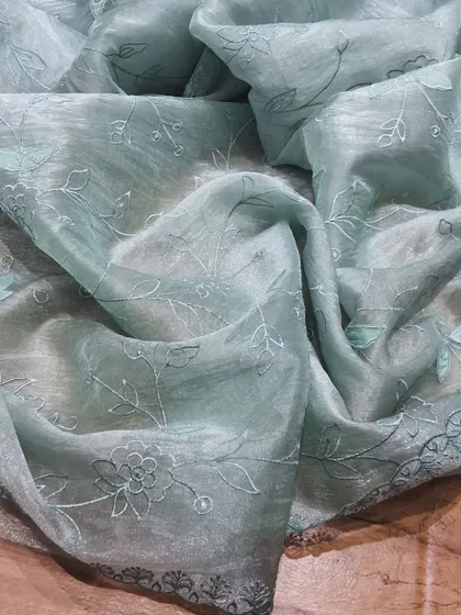 A pastel blue crush tissue saree with intricate tonal embroidery. This saree is the definition of understated elegance, perfect for those who love subtle details.