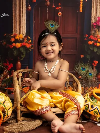 A happy 'Kanha' sitting in a wicker chair. The joy on his face is infectious, making this a perfect portrait to celebrate Krishna's birth.