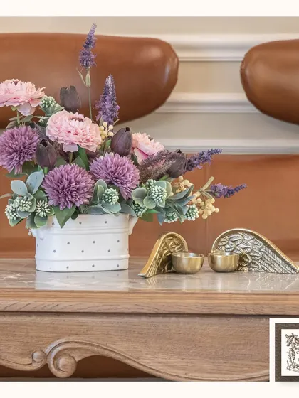 This arrangement of purple and pink artificial flowers, paired with winged candle holders, creates a beautiful and serene tabletop display. It's a perfect example of artful beauty that never fades.