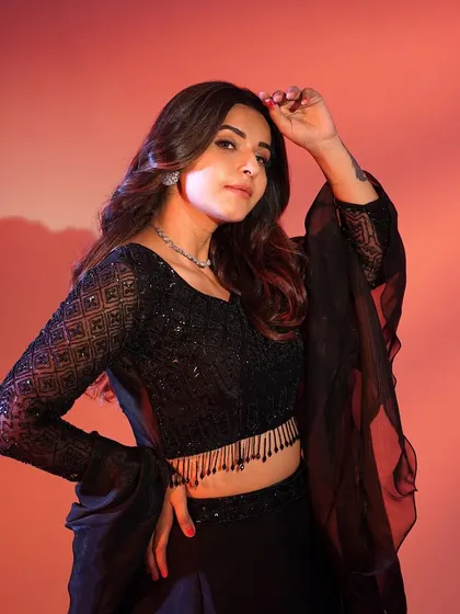 A powerful pose in the black lehenga. The dramatic sleeves and all-black look create a chic and sophisticated vibe.