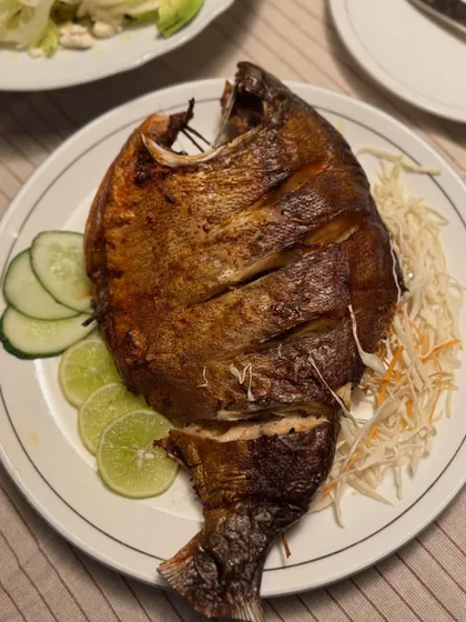 A beautifully roasted whole fish, scored to let the Naga spice marinade penetrate deep into the meat. It's served with a simple garnish of shredded cabbage, cucumber, and lime.