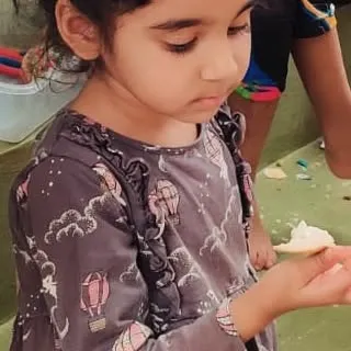 A young child curiously examines a piece of the freshly picked fruit, a new sensory experience of taste and texture.