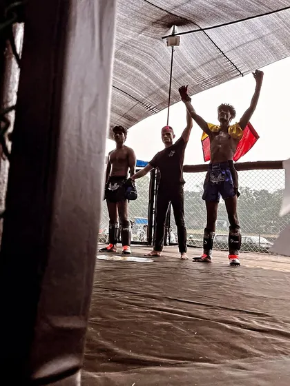 A coach raises the fighter's hands in victory. This partnership between coach and athlete is the foundation of our success.