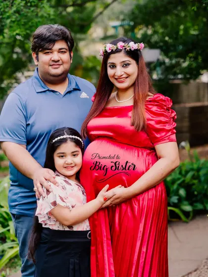"Promoted to Big Sister." Using a custom message on the baby bump is a sweet and creative way to include the older sibling in a maternity photoshoot and announce the growing family.