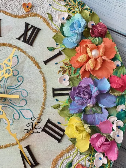 A detailed view of the sculpted flowers on the clock, showing a mix of orange, purple, and blue blossoms with pearl centers.