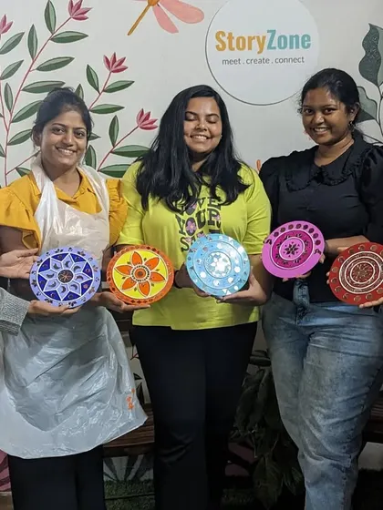A group of friends showing off their finished Lippan art, which shares a similar meditative quality with mandala art.