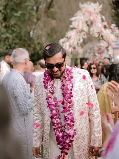 The groom's happy expression as he walks through a shower of petals, surrounded by his loved ones.