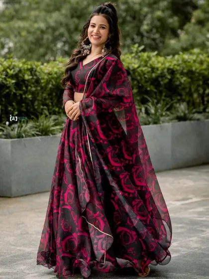 A full-length shot that shows off the beautiful black and pink floral lehenga. The outdoor setting adds a fresh and natural feel to this traditional outfit.