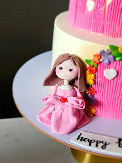 A detailed shot of the handmade princess figurine in her pink dress, part of the castle cake decoration.