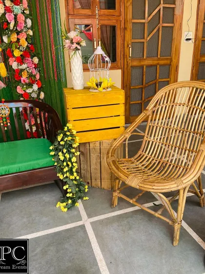 A detail shot of the side decor, featuring a cane chair and a yellow crate with a birdcage, adding to the bohemian charm of the Mehndi setup.