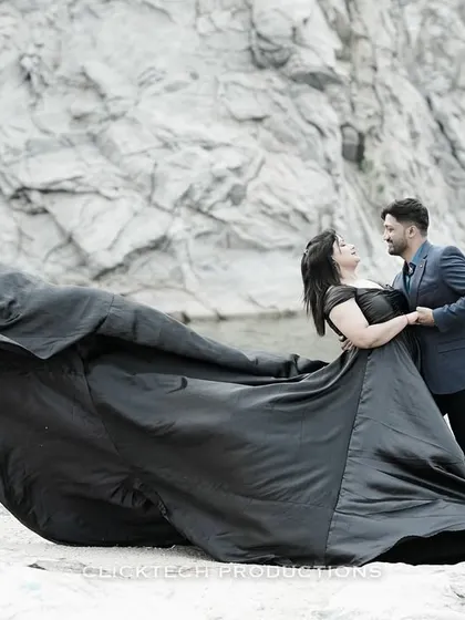 A romantic and dynamic shot of a couple by a quarry, with the bride's black gown caught in motion, adding a sense of cinematic flair.