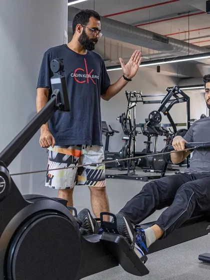 A trainee learns proper rowing machine technique, a critical component of cardiovascular conditioning.