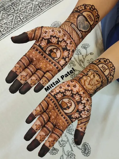 A spiritual baby shower design featuring Lord Ganesha on one arm and the word "Maa" on the other. The palms are decorated with peacock and lotus mandalas.