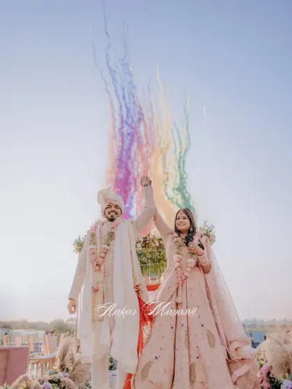 A beautiful, wide shot of the couple's Varmaala, with a rainbow of smoke creating a magical arc above them.