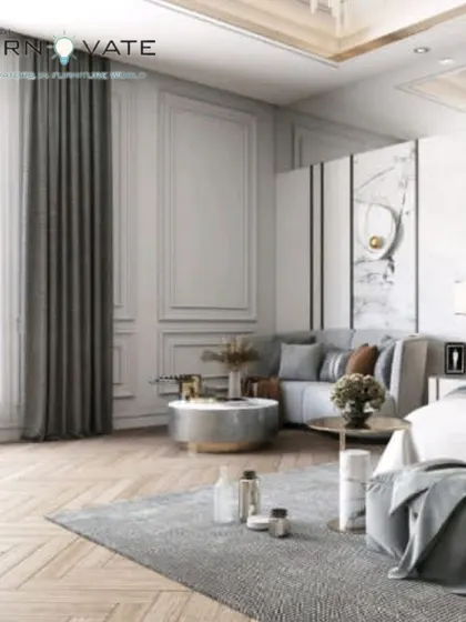 An elegant bedroom with classic wall molding and a sophisticated grey color palette. The design includes a comfortable seating area, creating a luxurious, hotel-like suite.