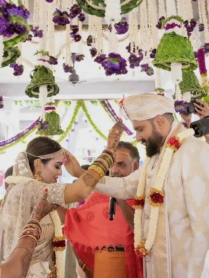 A sacred moment during the Muhurtham ceremony, with the couple framed by the stunning floral canopy above.