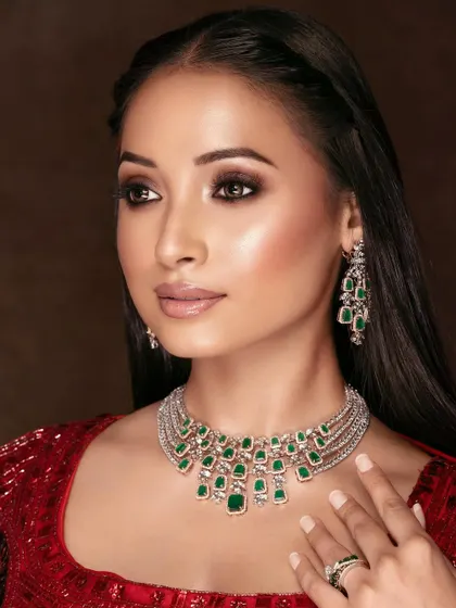 An elegant pose that highlights the neckline and the stunning emerald necklace, showing the jewelry in beautiful detail.