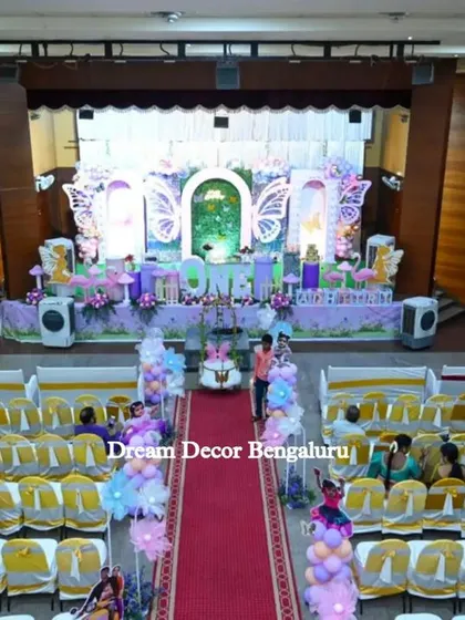 A wide shot of the butterfly-themed party hall, showing the impressive scale of the stage and seating arrangement.