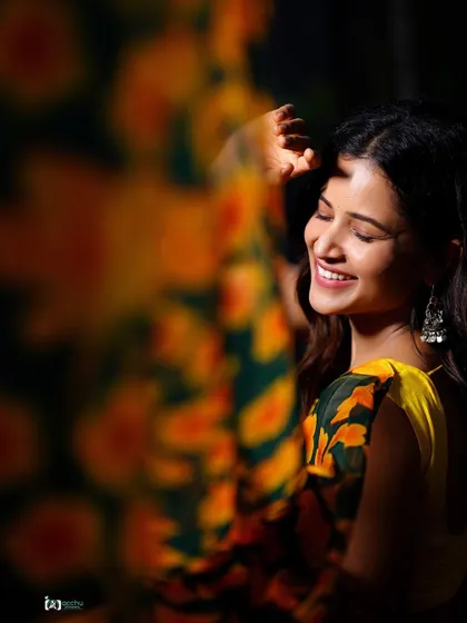 This artistic shot uses a foreground blur to create a sense of intimacy and focus on the subject's happy expression. It’s a creative take on a traditional portrait.
