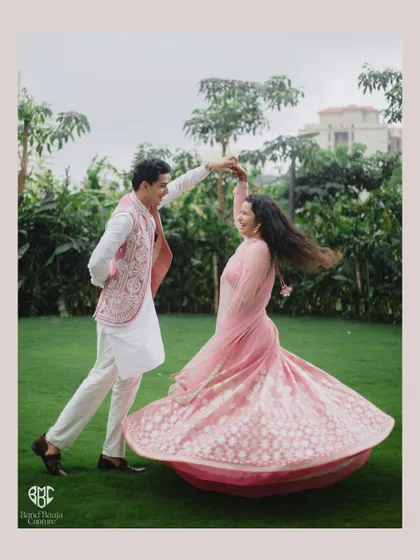 A beautiful, dynamic shot of the groom twirling his bride on a lush green lawn. The movement of her lehenga and their joyful expressions make this a perfect Roka portrait.