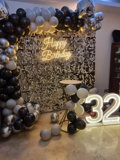 A classic black, white, and silver theme for a 32nd birthday, featuring a sequin wall, balloon arch, and marquee numbers.