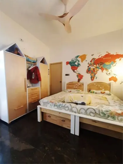A kid's bedroom featuring a house-shaped wardrobe and a bed with under-cot storage. The world map on the wall adds a fun and educational element to the room's decor.