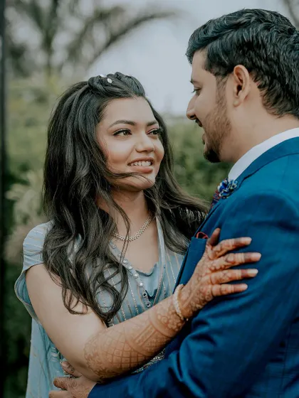 A close-up shot capturing the loving gaze between the couple. Her intricate mehendi is visible as she holds him, adding a traditional touch to this sweet, candid moment from their engagement photoshoot.