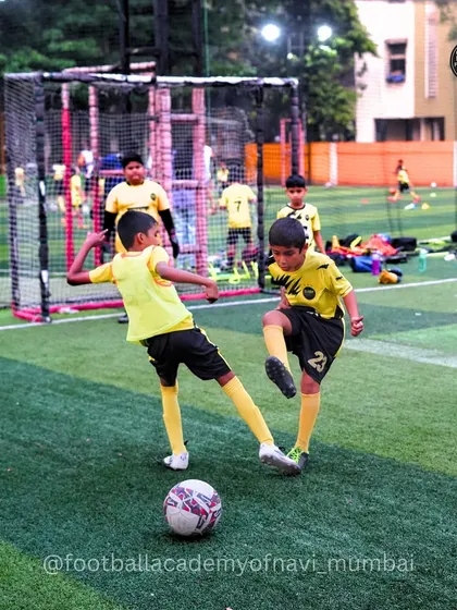 A friendly tussle for the ball between two young players. These moments build resilience and a competitive spirit.