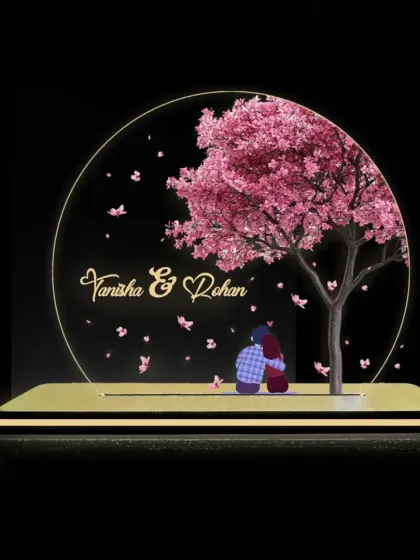 A romantic LED lamp featuring a silhouette of a couple under a cherry blossom tree, personalized with their names.