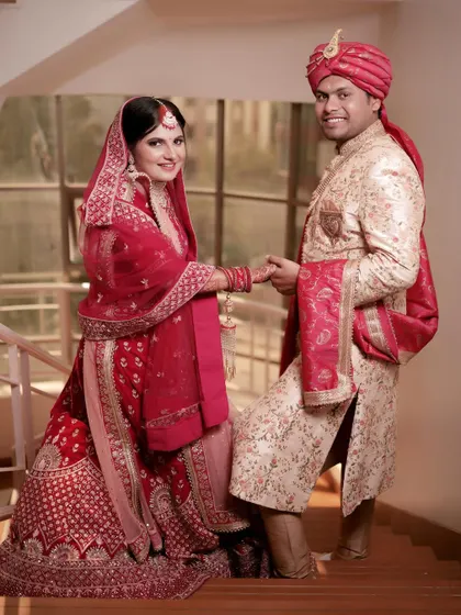A classic wedding portrait on a staircase. The couple holds hands, with the groom leading his bride, symbolizing the start of their journey together.