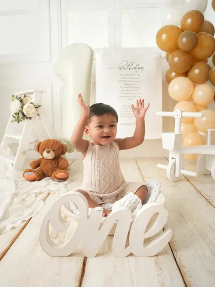 Hands up if you're one. This joyful shot captures the pure excitement of a first birthday celebration.