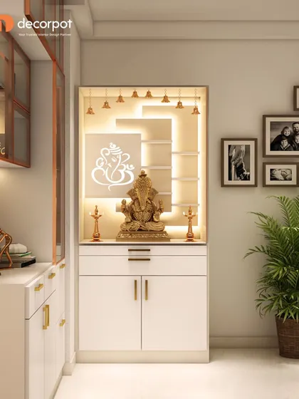 A clean and elegant pooja unit in white, featuring a backlit Ganesha design and hanging bells. The gold handles on the drawers add a subtle touch of luxury.