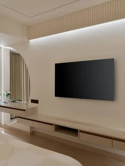 In the master bedroom, we designed an integrated TV and vanity unit with a unique semi-circular mirror, all set against a backdrop of soft, ambient lighting and textured walls.