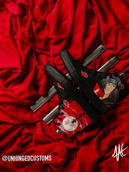 Itachi Uchiha on a pair of black Converse high-tops. This design captures the iconic, tragic scene of Itachi before the Uchiha clan massacre, set against a blood-red moon.