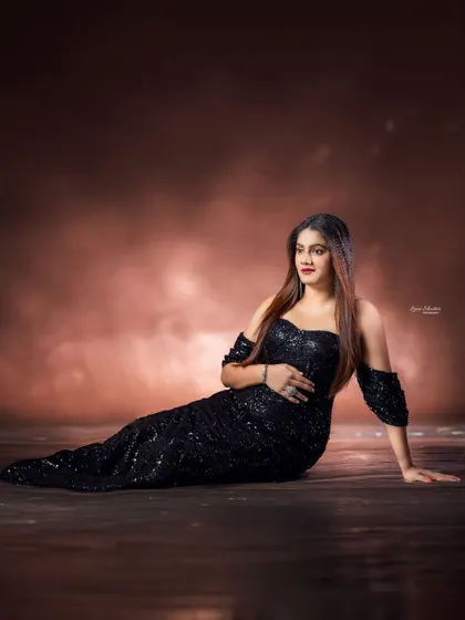 A glamorous reclining pose that showcases the beautiful lines of the sequined black gown. The textured backdrop adds depth and a moody, sophisticated feel.
