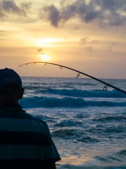 A fisherman at sunset on the coast of Sri Lanka. This image captures a timeless, patient moment against the backdrop of a beautiful sky and rolling waves.