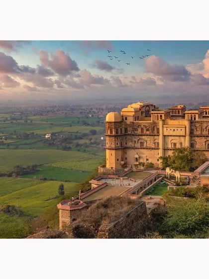 An expansive daytime view of the fort perched above the lush green valley. This image showcases the property's stunning location and architectural dominance in the landscape.