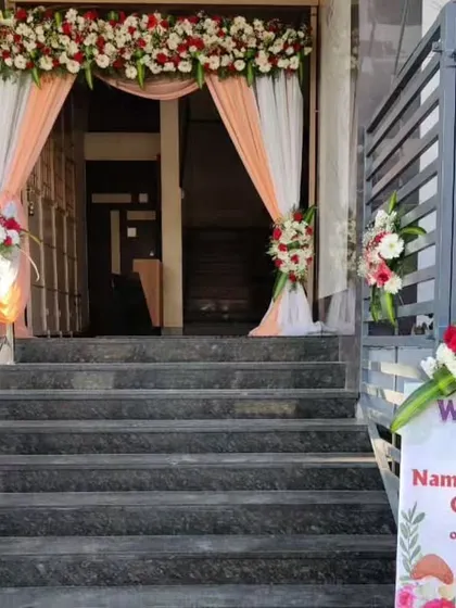 We ensure the welcome is as special as the event itself. Here, we designed the entrance decor for a naming ceremony, complete with a custom welcome sign, draped fabrics, and floral arrangements on the stairs.