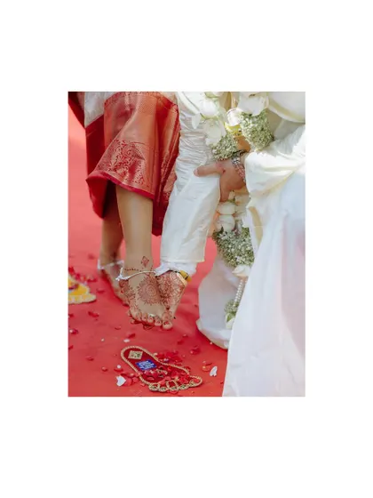 A detail shot of the couple's feet during a traditional wedding ritual on a red carpet.