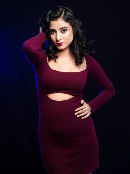 A full-body shot showcasing the complete look, with a stylish cutout dress that complements the glamorous hair and makeup.