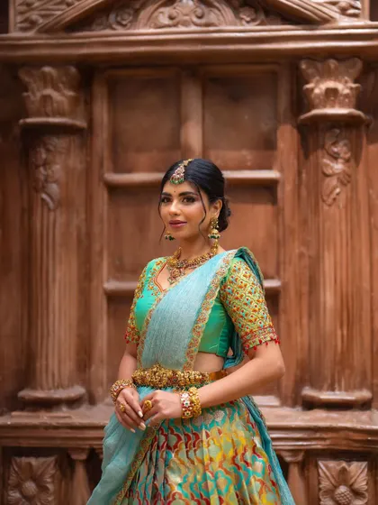 A classic portrait pose in the same light blue half saree. The bride's confident stance and the intricate details of her outfit are the focus.