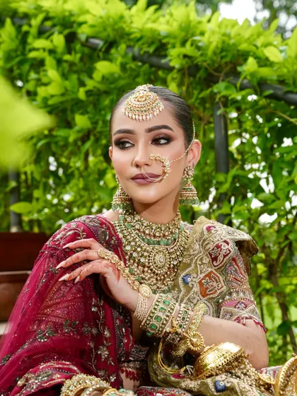 A candid, elegant pose showing off the complete bridal look. The makeup remains flawless, with a focus on the eyes and the overall radiant finish that complements her traditional attire.
